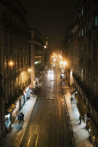 High angle view of illuminated street amidst buildings at night