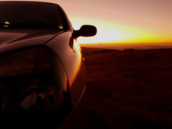 Close-up of car on landscape against sunset sky