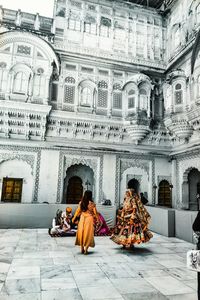 People sitting on the wall of a historical building