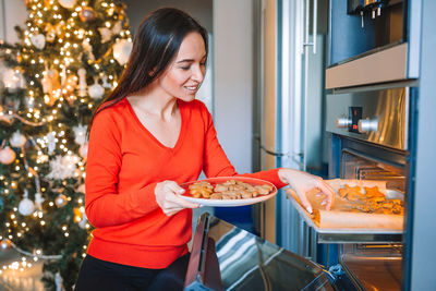 Portrait of young woman preparing food on christmas tree