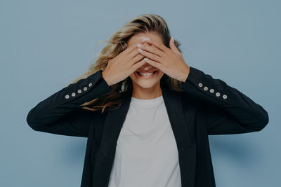 Portrait of young woman standing against blue background