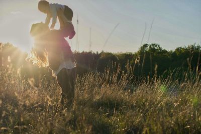 Full length of silhouette woman on field against sky during sunset