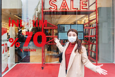 Portrait of happy woman wearing mask standing by shopping mall