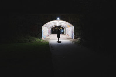 Rear view of man walking in tunnel