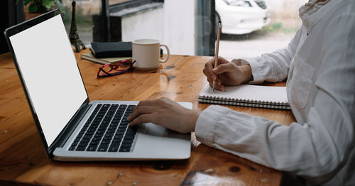 Midsection of man using laptop on table