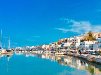 Sailboats moored in sea against blue sky