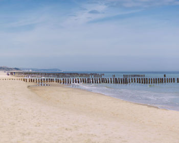 Wooden posts at beach against sky