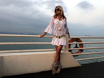 Woman standing by railing against sea