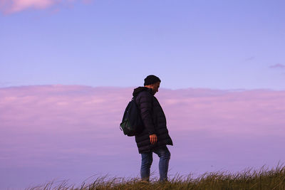 Rear view of man standing on field against sky