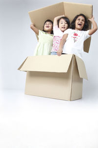 Smiling girls sitting in box against white background