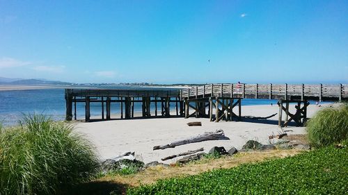 Pier over sea against clear blue sky