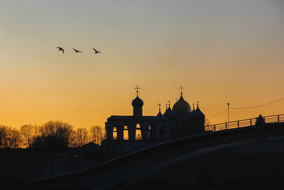 Silhouette birds flying against sky during sunset