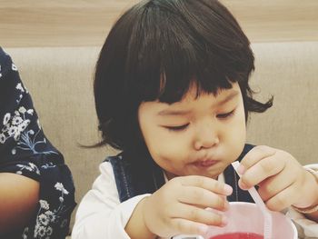 Cute baby girl drinking juice at restaurant