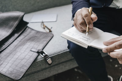 Close-up of businessman writing and drawing in notebook