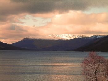 Scenic view of lake and mountains against sky during sunset