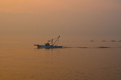 Sailboat in sea against sky during sunset