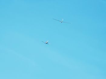 Low angle view of airplanes flying in clear blue sky