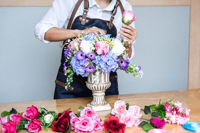 Midsection of florist arranging flowers in urn