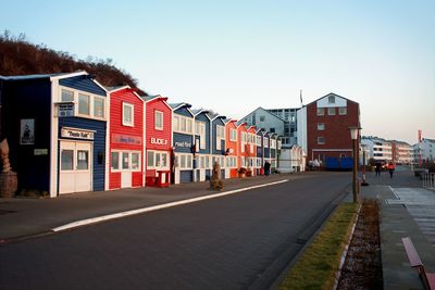 Empty road by buildings against sky in city