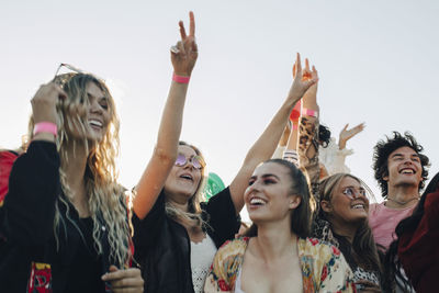 Cheerful people enjoying music concert against sky in summer