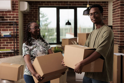 Portrait of man holding box standing by woman at home