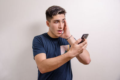 Young man using smart phone against white background