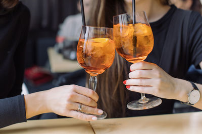 Midsection of friends toasting drinks in restaurant