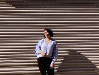 Young woman standing against shutter