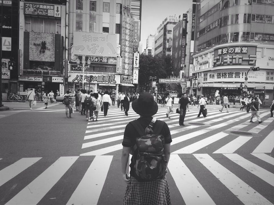 city, building exterior, street, architecture, built structure, city life, walking, men, large group of people, person, zebra crossing, city street, road marking, road, transportation, text, lifestyles, pedestrian, communication