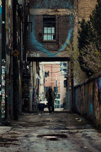 Rear view of woman walking on street amidst buildings