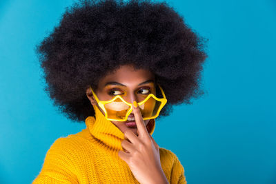 Smiling young woman wearing sunglasses against blue background
