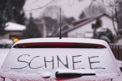 Text on snow covered car rear windshield during winter