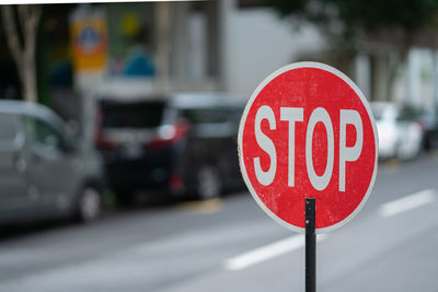 A closeup of a red stop sign on the road with blurred background