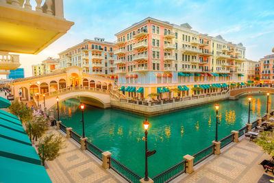 View of swimming pool bridge over canal against buildings