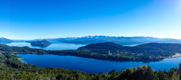 Scenic view of lake and mountains against clear blue sky