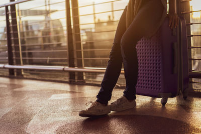 Low section of woman standing on railing