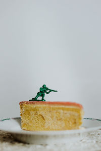Toy soldier standing on the top of a piece of cake - close up of figurine aginst white background