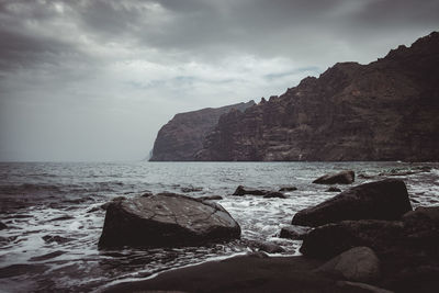 Rocks on shore by sea against sky