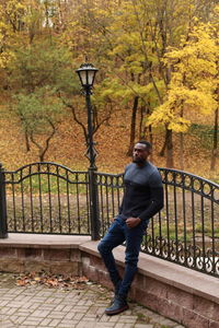 Full length of man standing by railing during autumn