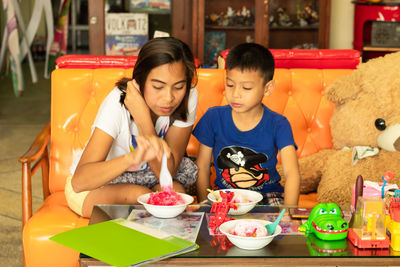 Mother and son having dessert while sitting on sofa at home