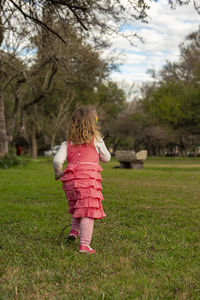 Rear view of woman with pink umbrella on field