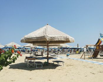 Thatched roof on beach against clear blue sky