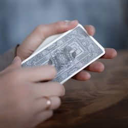 Close-up of hand holding paper with tattoo on table