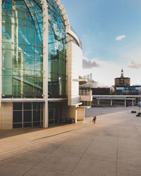 People walking in modern building against sky