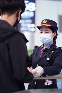 Woman in uniform wearing mask assisting man