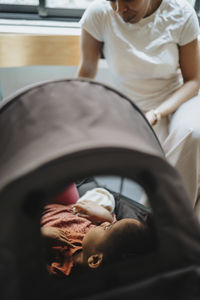 Mother talking with ill daughter lying in stroller at waiting room