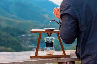 Man and coffee cup on table against mountains