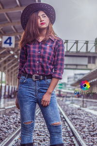 Full length of beautiful woman standing on railroad tracks
