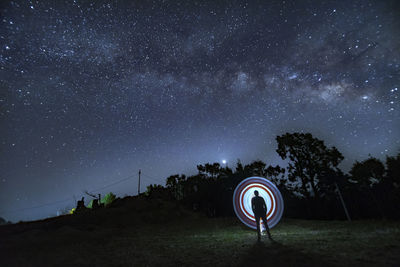 Rear view of man standing against sky at night