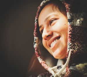 Close-up portrait of smiling woman against black background